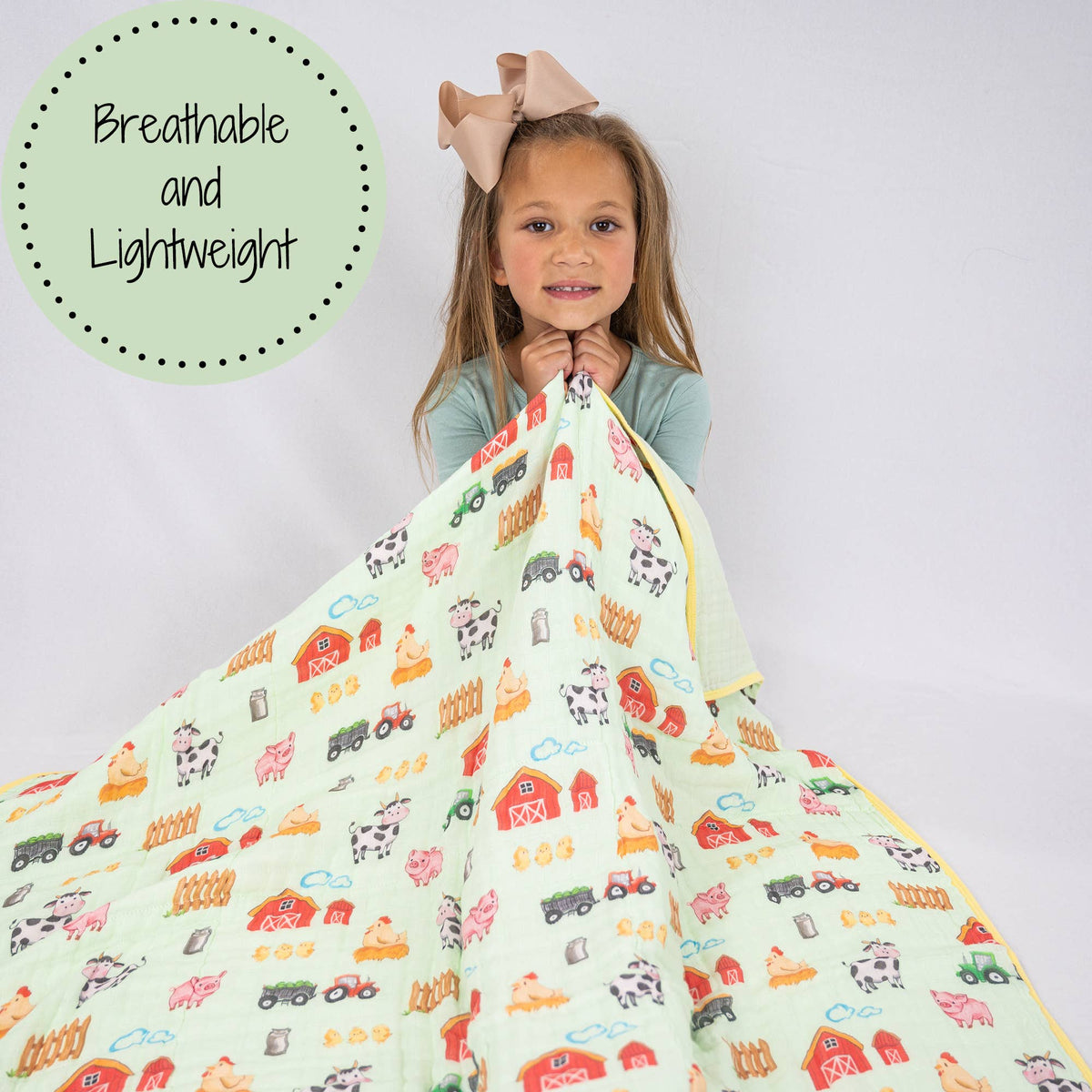 Child holding a colorful blanket with farm animal patterns on a plain background