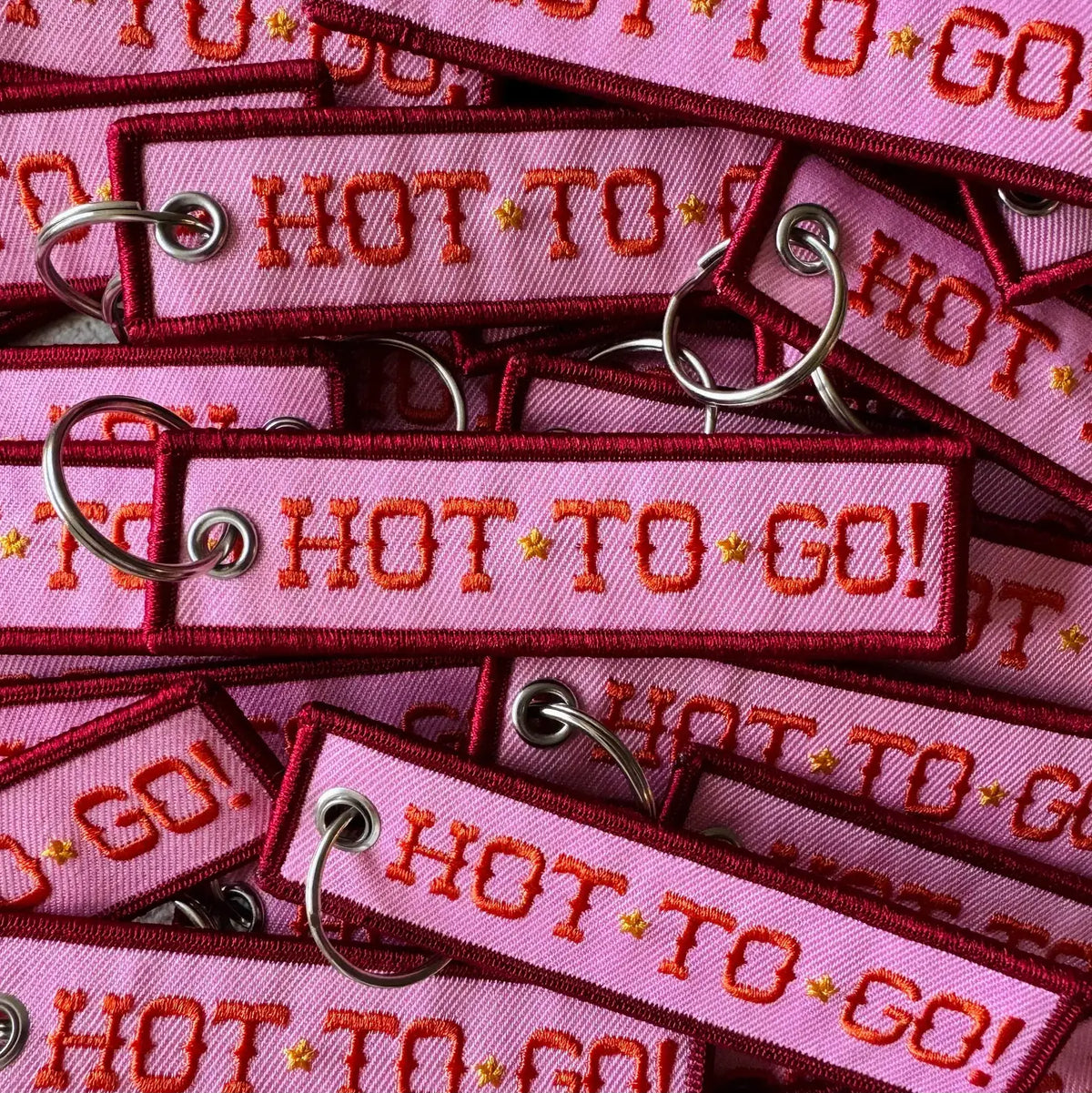 Pink keychains with 'HOT TO GO!' text on a pink background
