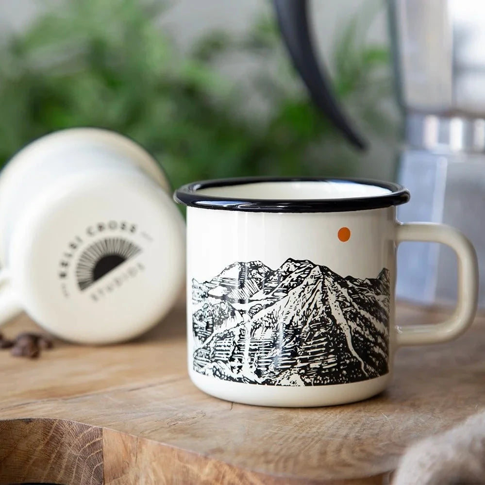 Cream enamel mug with black mountain design and black rim.