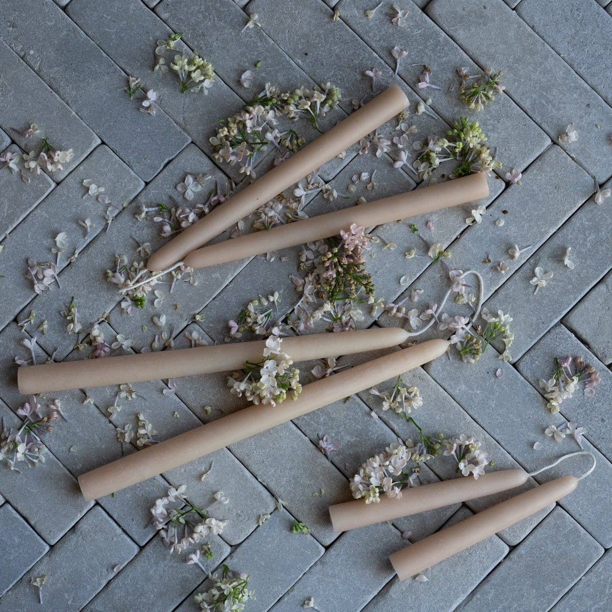 Four wooden dowels on a stone surface with scattered flowers