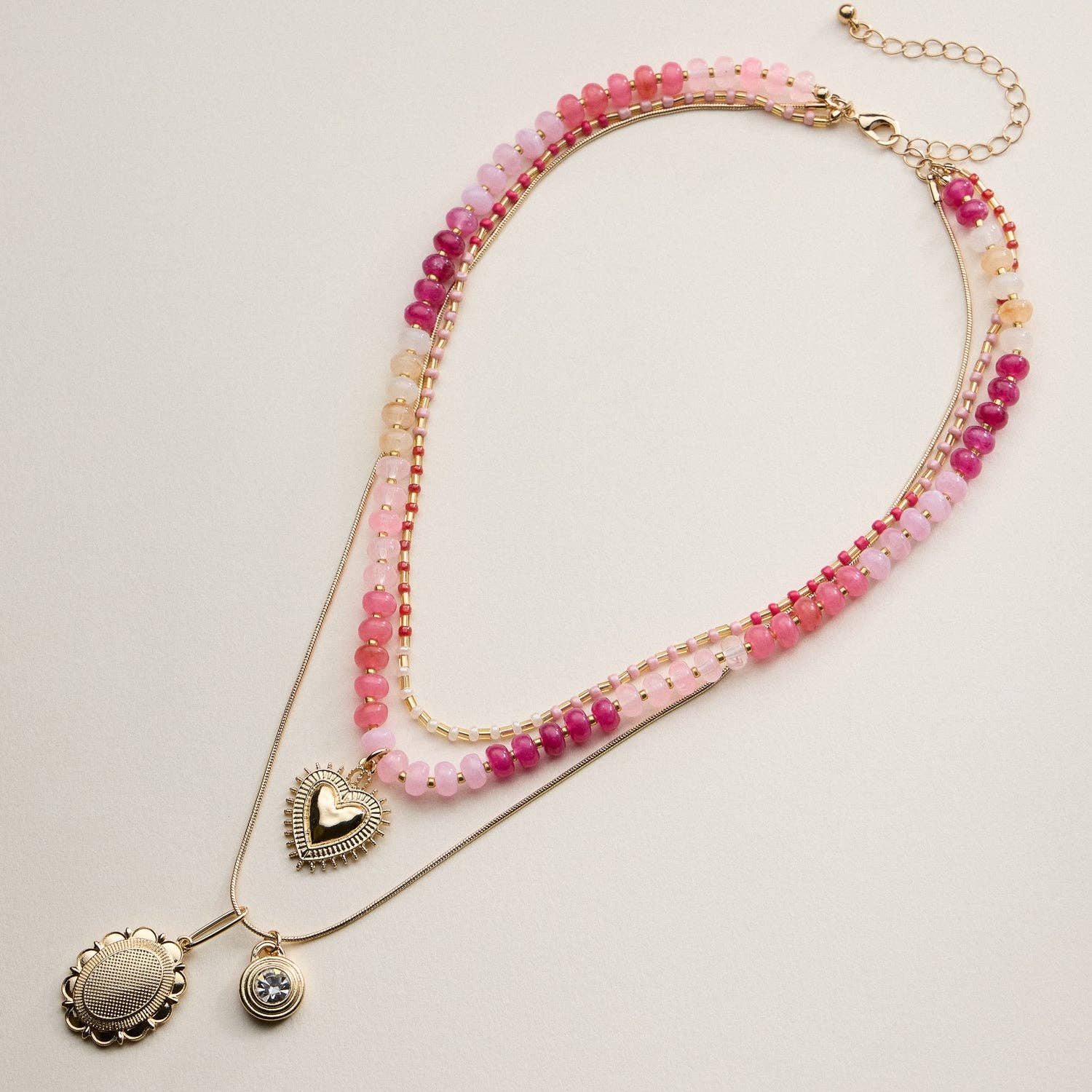 This layered necklace set combines texture and shine for an effortlessly chic look. Designed with strands of glass beads, gold cube accents, and delicate snake chains, it features a mix of heart and round pendants for a modern romantic finish. The adjustable chain and secure lobster clasp ensure a comfortable fit, perfect for everyday wear or special occasions.
Details:
Material: Glass beads with gold-tone metal chains and pendants
Design: Three-layer necklace with beaded strands and charm pendants