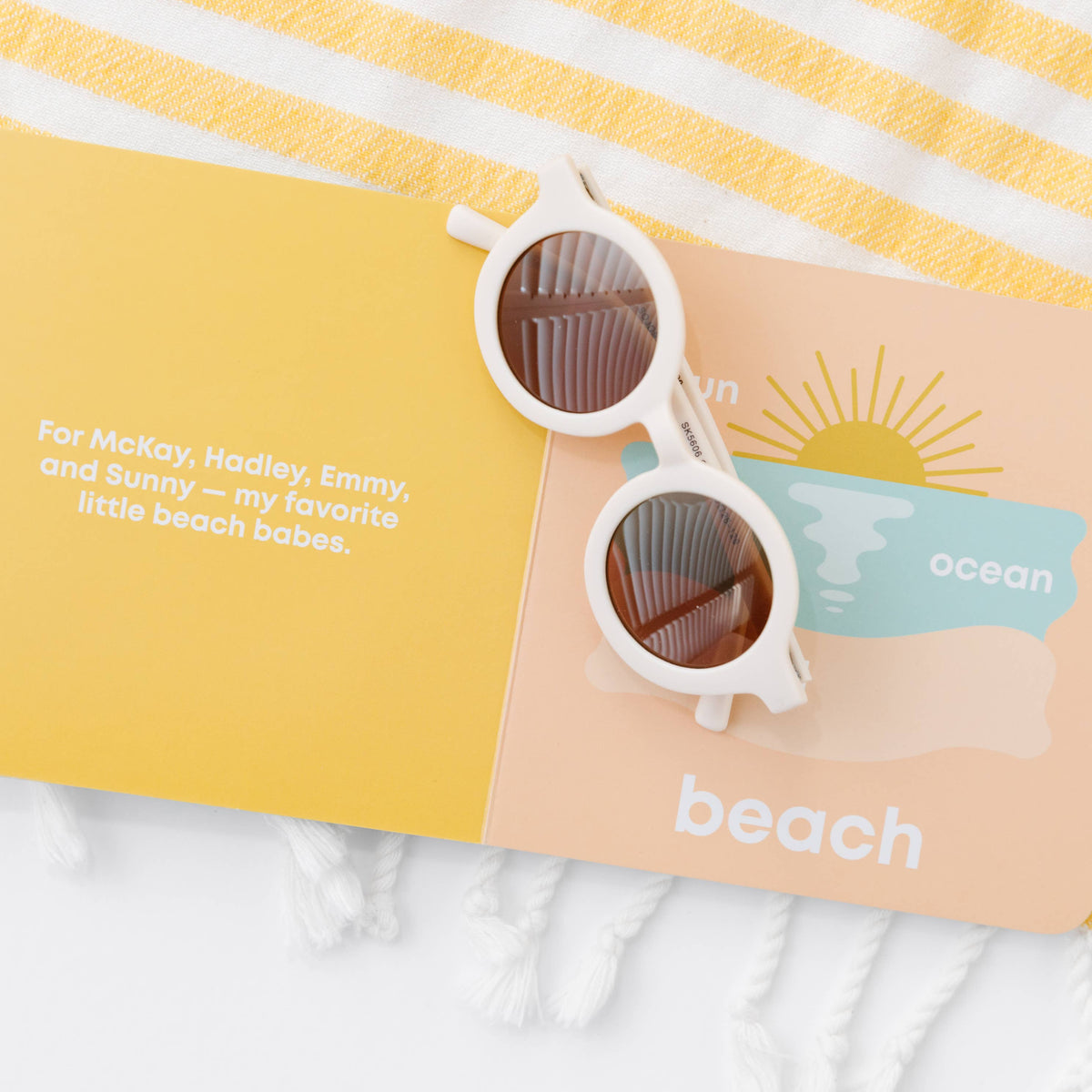 Sunglasses on a personalized beach towel with text and branding.
