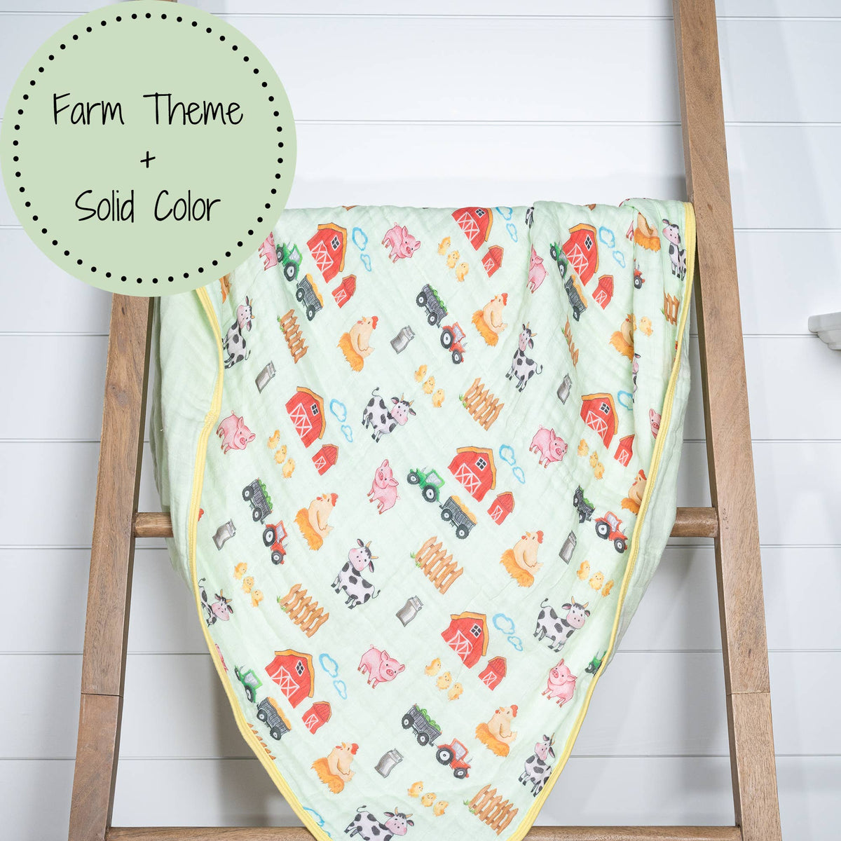 Baby blanket with farm-themed design on a wooden ladder against a white background