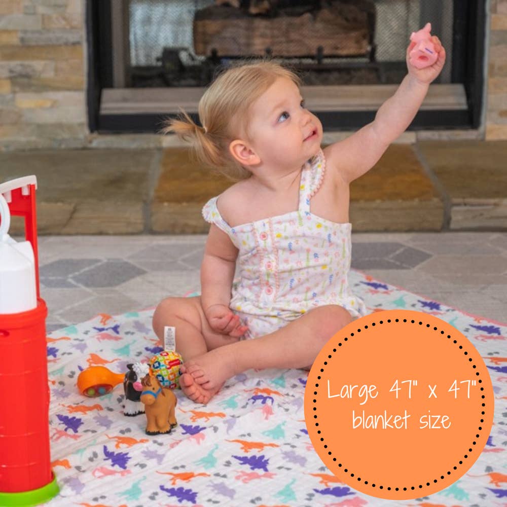 Child playing on a colorful blanket with toys, fireplace in the background