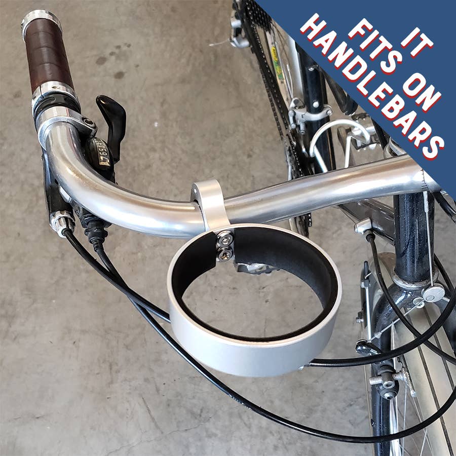 Bicycle handlebar with a cup holder attached, on a concrete floor.
