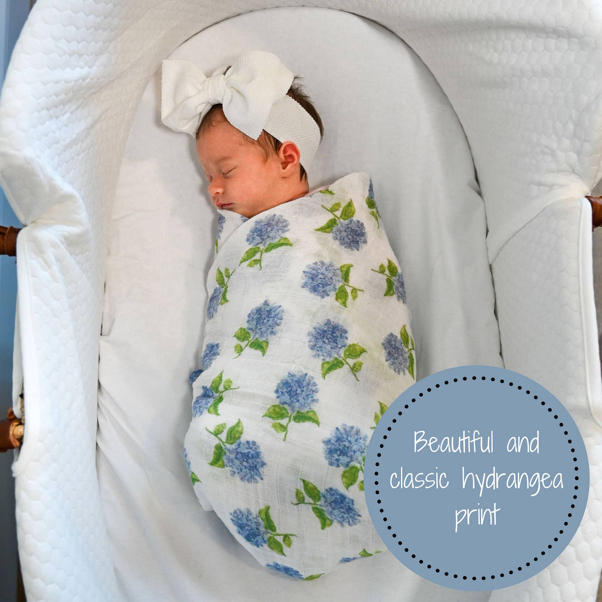 Newborn baby wrapped in a floral blanket with a white bow, lying in a crib.