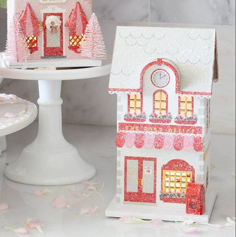 Welcome to the cutest corner of your Valentine's Day celebration! This charming Post Office paper house brings nostalgic magic to your village display. Perfect for creating an enchanting holiday scene, this detailed piece adds character and whimsy to any festive setup. Whether you're building a complete village display or adding a special touch to your party décor, this post office is perfect for your shelf.
Details:
Red, pink, and cream post office
Post office is 4" wide x 3.5" deep x 6.5" tall