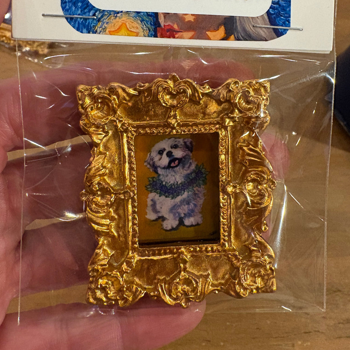 Gold-framed miniature painting of a dog held in clear plastic packaging with Sabrina Crettes card.