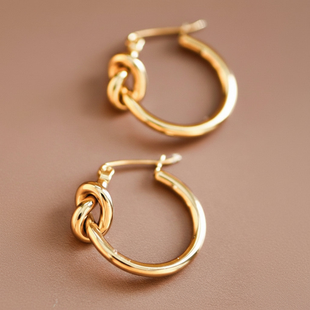 Elevate your everyday look with these 18K gold-dipped stainless steel knot hoop earrings, measuring approximately 0.9" in length. Crafted for durability and comfort, they're hypoallergenic, waterproof, and tarnish-resistant—perfect for sensitive skin and active lifestyles. To maintain their lustrous finish, avoid prolonged contact with lotions, perfumes, and cleaning products. A versatile essential that transitions seamlessly from day to night.