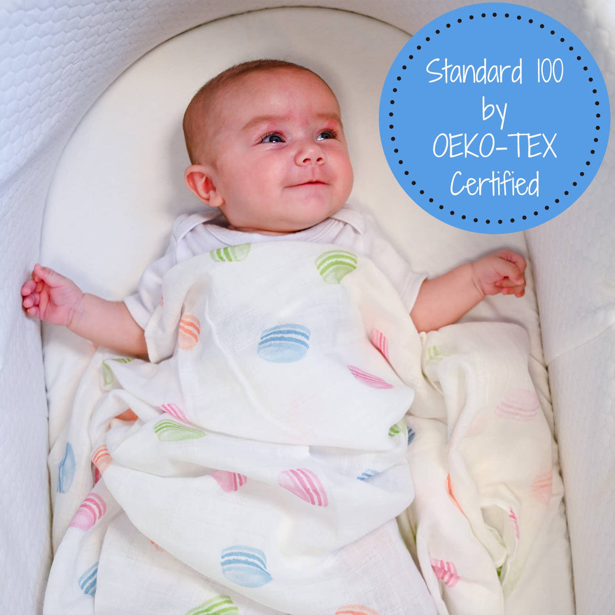 Baby wrapped in a colorful blanket with OEKO-TEX certification label.