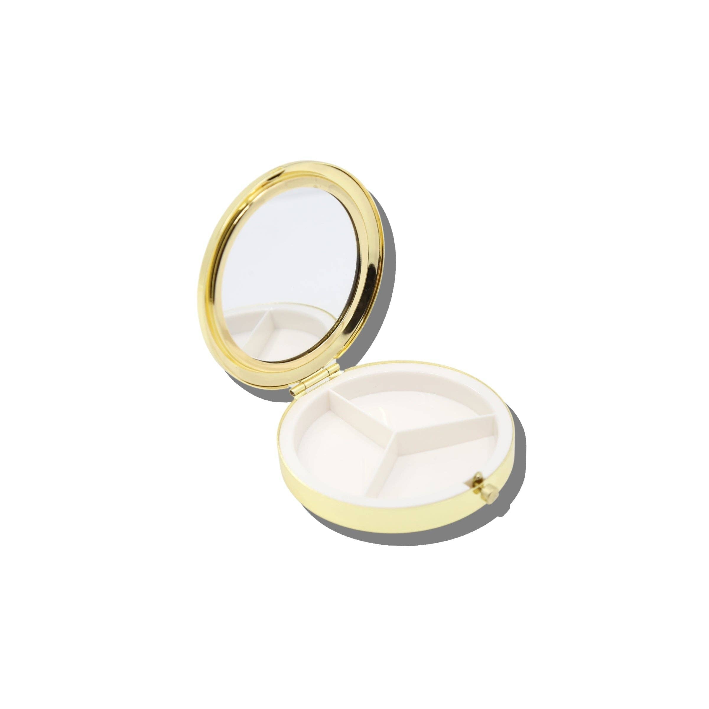 An open round compact case with a gold-tone metal frame and mirror, showing a white interior with three compartments, on a plain white background.
