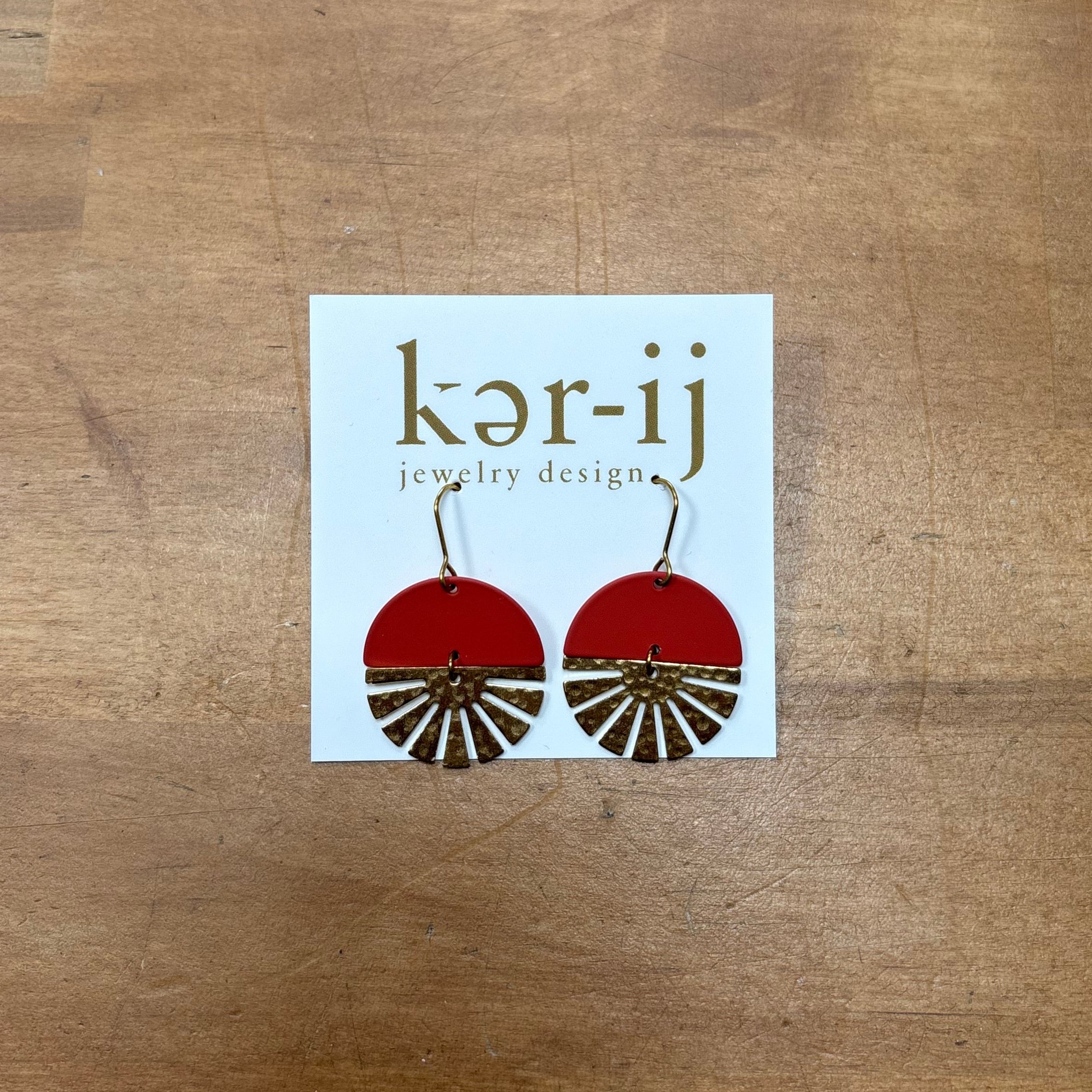 Rayya Earrings - Rusty orange Enameled. Inspired by the moon and the sun, these earrings feature red enameled semi-circle with a raw brass sun shine-esque charm. Modern and simple with just the right flair.