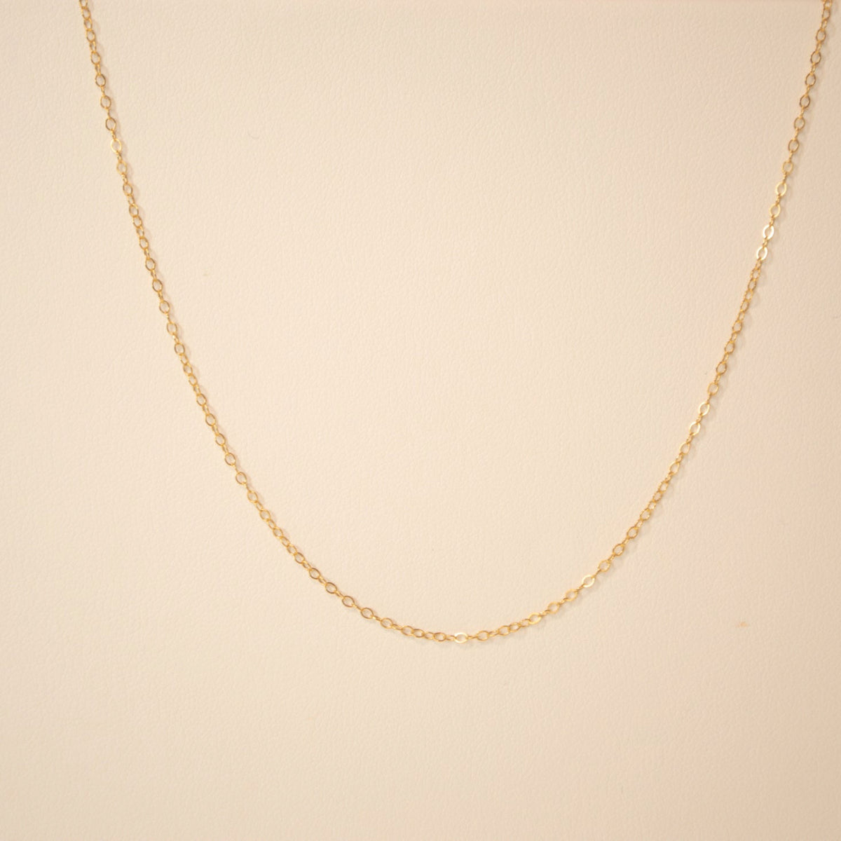 Gold chain against an off white back ground.