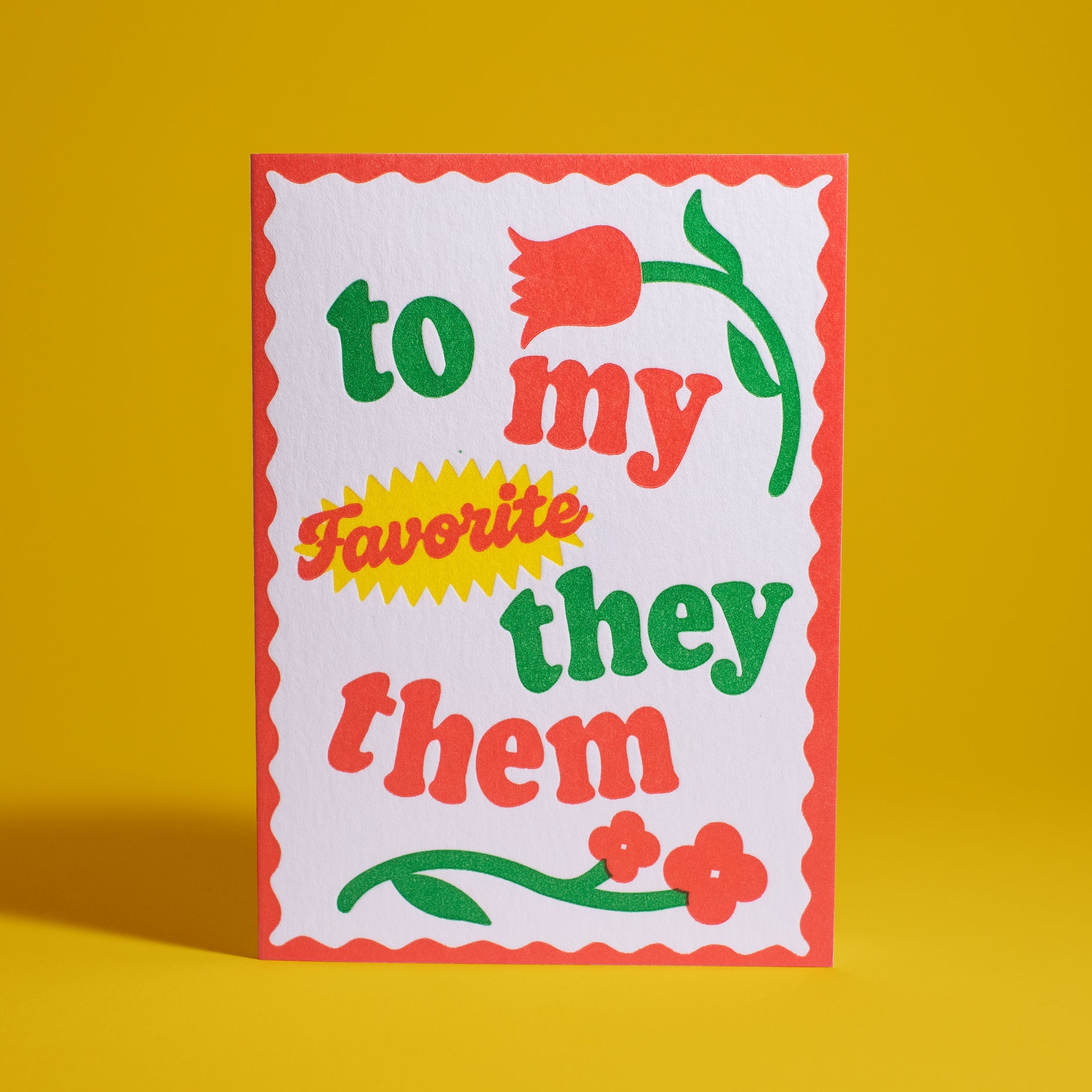 White card with red scallop edging. In alternating red and green lettering says "To my favorite they them". Red flowers part of design.