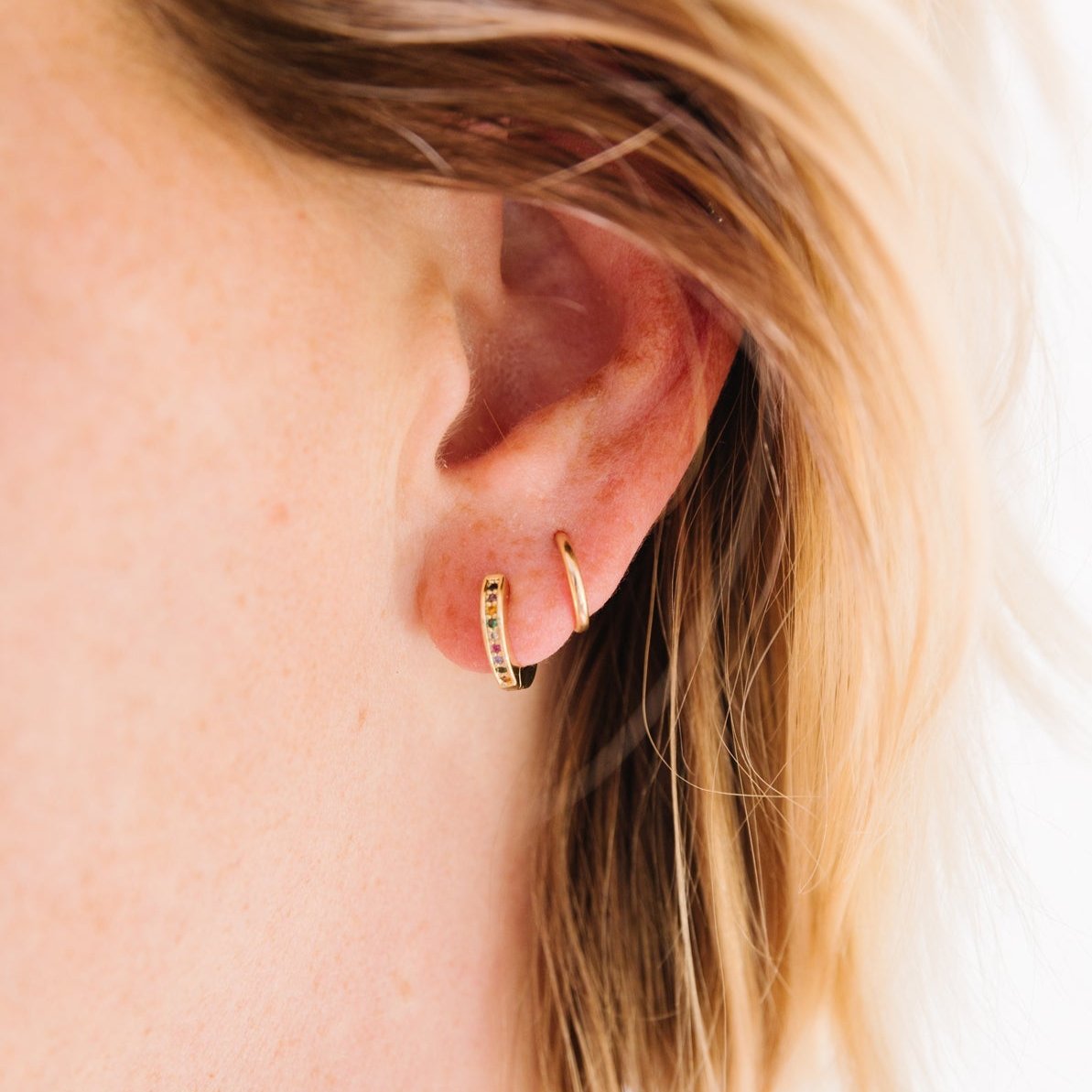 14k Gold Filled 12 mm huggie clasp Safe for sensitive skin Unique clasp has no post when earrings are closed, allowing for comfortable wear and sleep without having to remove earrings Multicolored bejeweld stones are 2 mm Perfect for mulitple piercings Freaking cute and freaking tiny