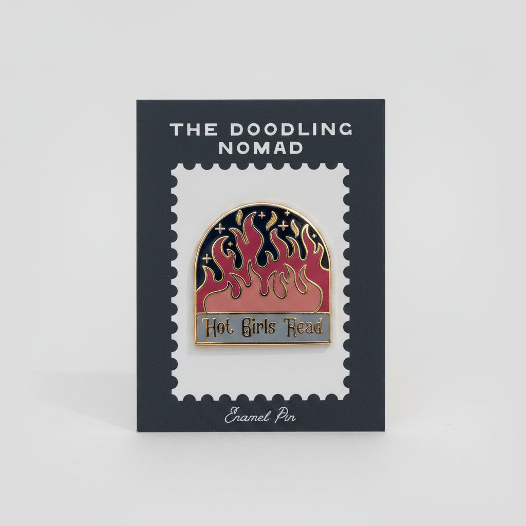 Enamel pin with a black background and red flames, with the words "Hot girls read" in gold.
