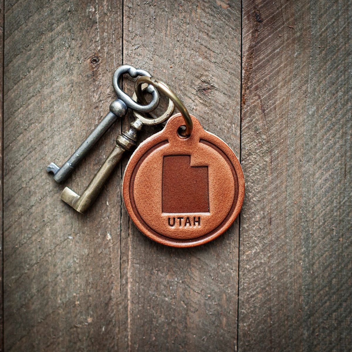 This Utah themed leather keychain comes in a perfect circle shape. Our leather keychains are cut and pressed by hand from some of the thickest and finest harness leather available, and patina beautifully as they age.
Size: 2”
Hardware: Antique Bronze 1 inch hinged keyring