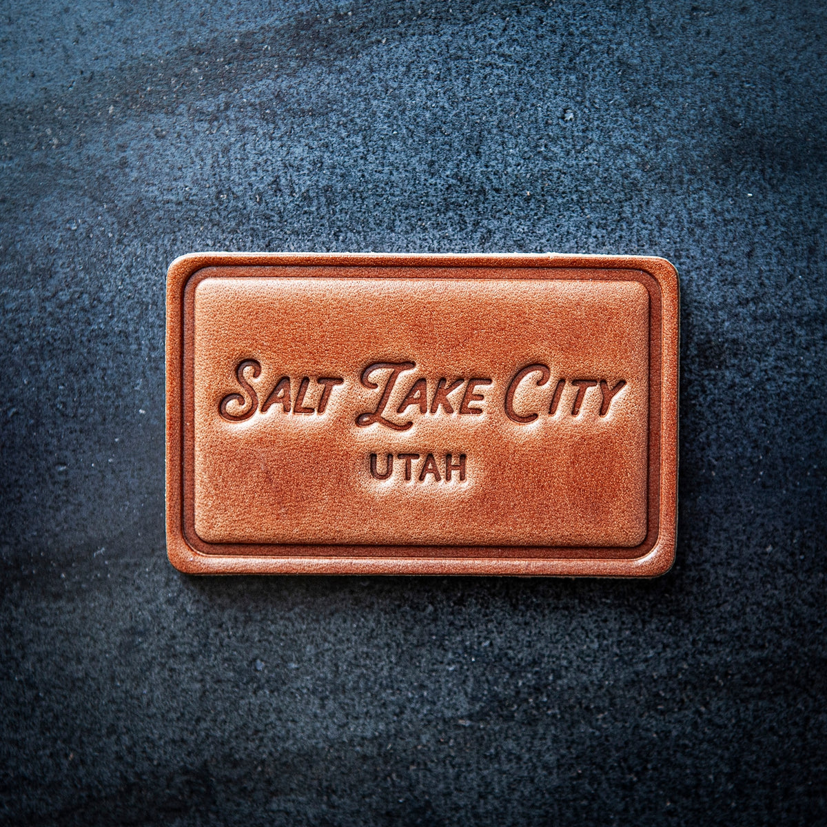 This leather magnet comes in a block style featuring “Salt Lake City, Utah” in beautiful calligraphy. Our leather magnets are cut and embossed from some of the thickest and finest harness leather available, and patina beautifully as they age.
Size: 2.8” x 1.75”
Magnet: Neodymium