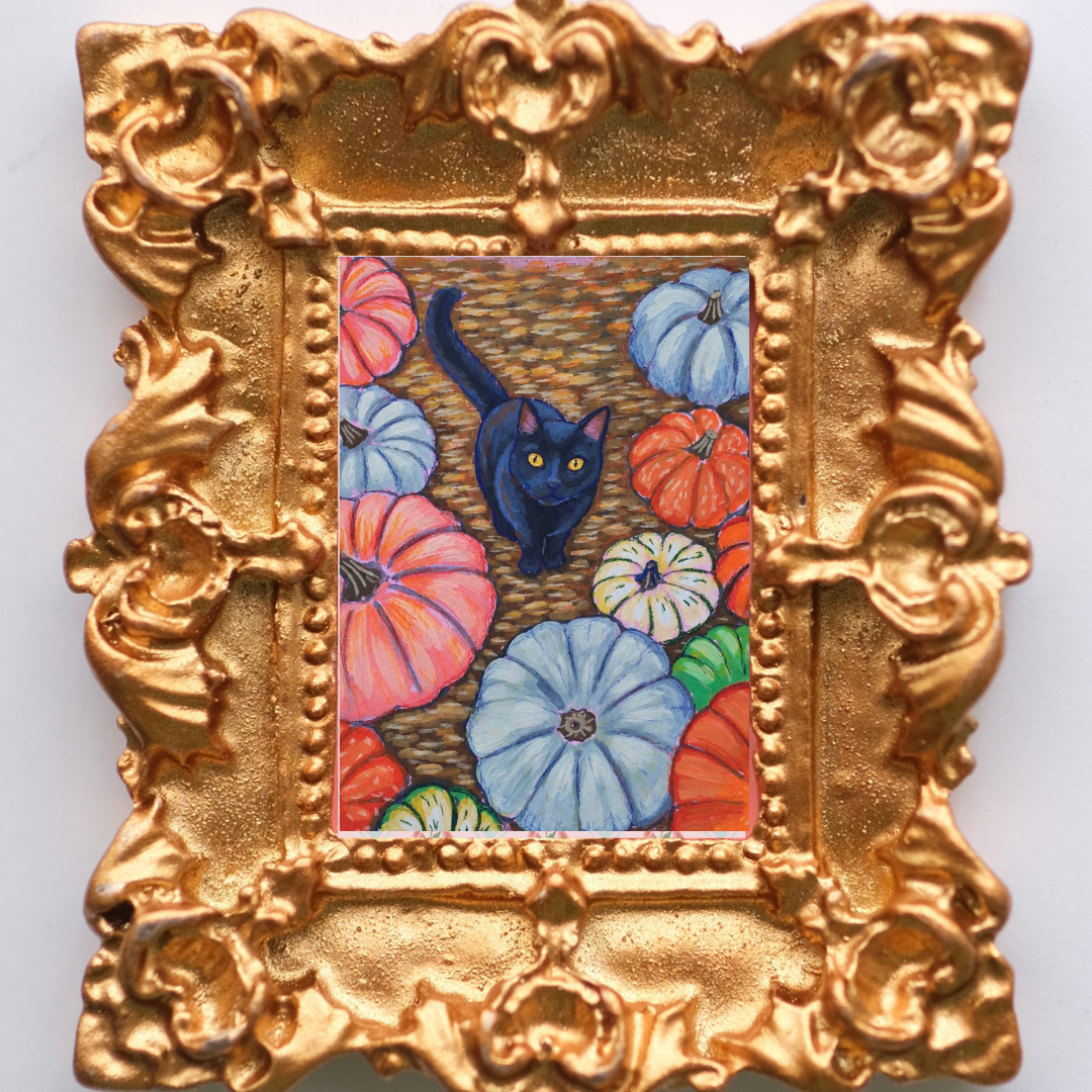 Mini gold framed magnet of a black cat amongst colorful pumpkins.
