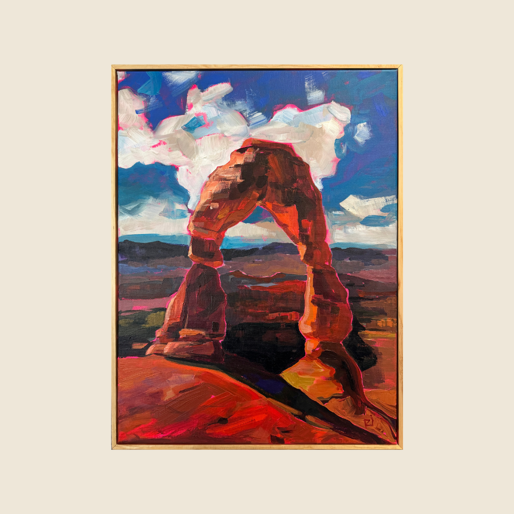 Delicate Arch with dramatic sunlight casting shadows in to the foreground. Blue skies with white fluffly clouds. Mountain vistsas in the back ground.