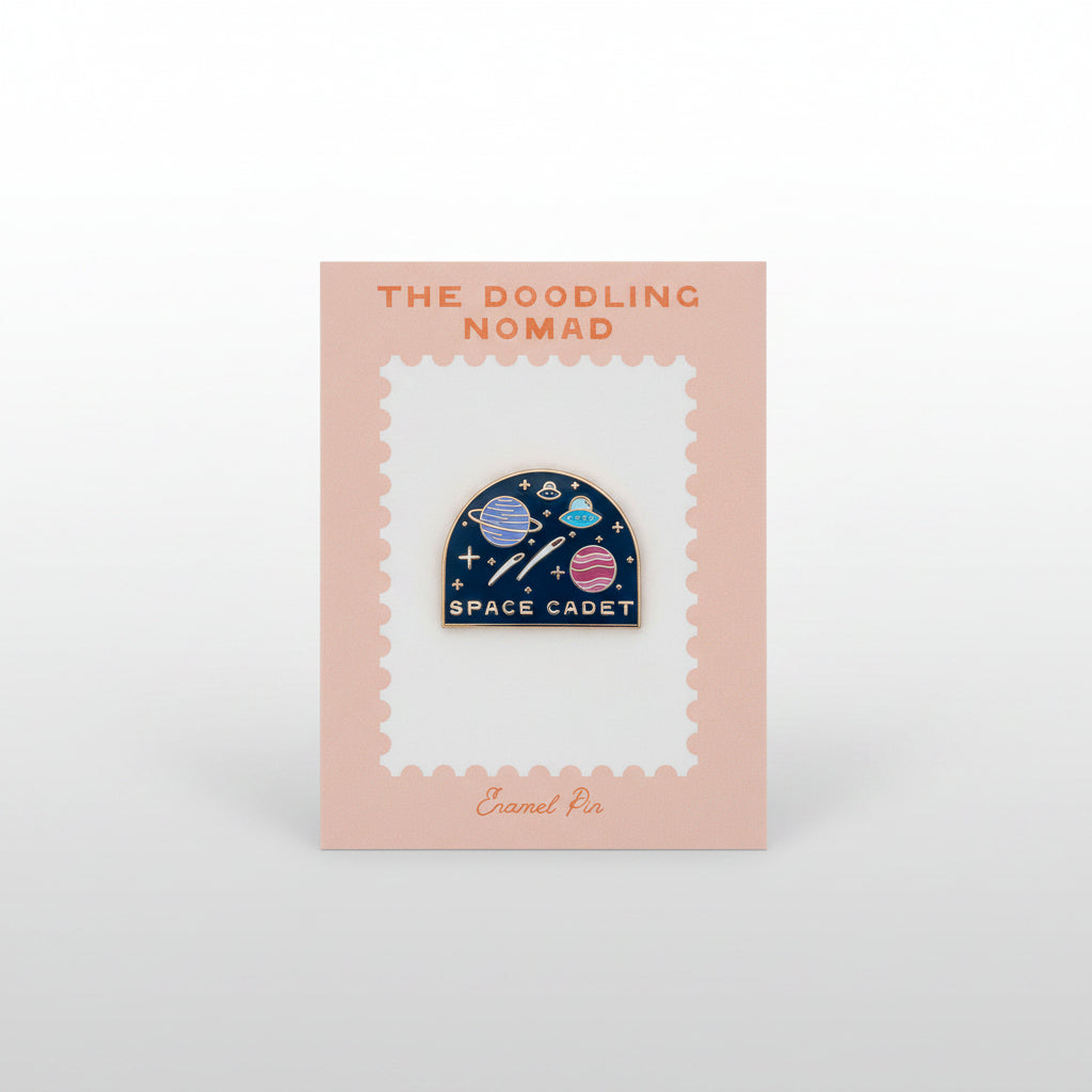 Enamel pin with planets and stars, in a black background, and the words "Space Cadet" in gold.