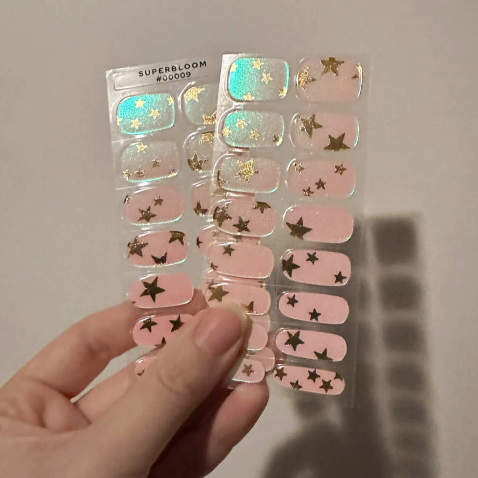 Light pink pearly base with gold metallic stars and an iridescent finish that changes in the light. Perfect for Holiday parties! 30 nail wraps Lasts up to 3 weeks Opaque pearl base color, gold metallic stars, and iridescent shimmery top coat Made of 100% UV gel polish Vegan, cruelty-free, non-toxic