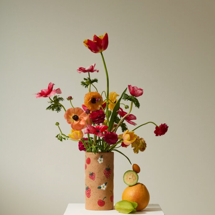 Vase with colorful flowers and fruits on a neutral background