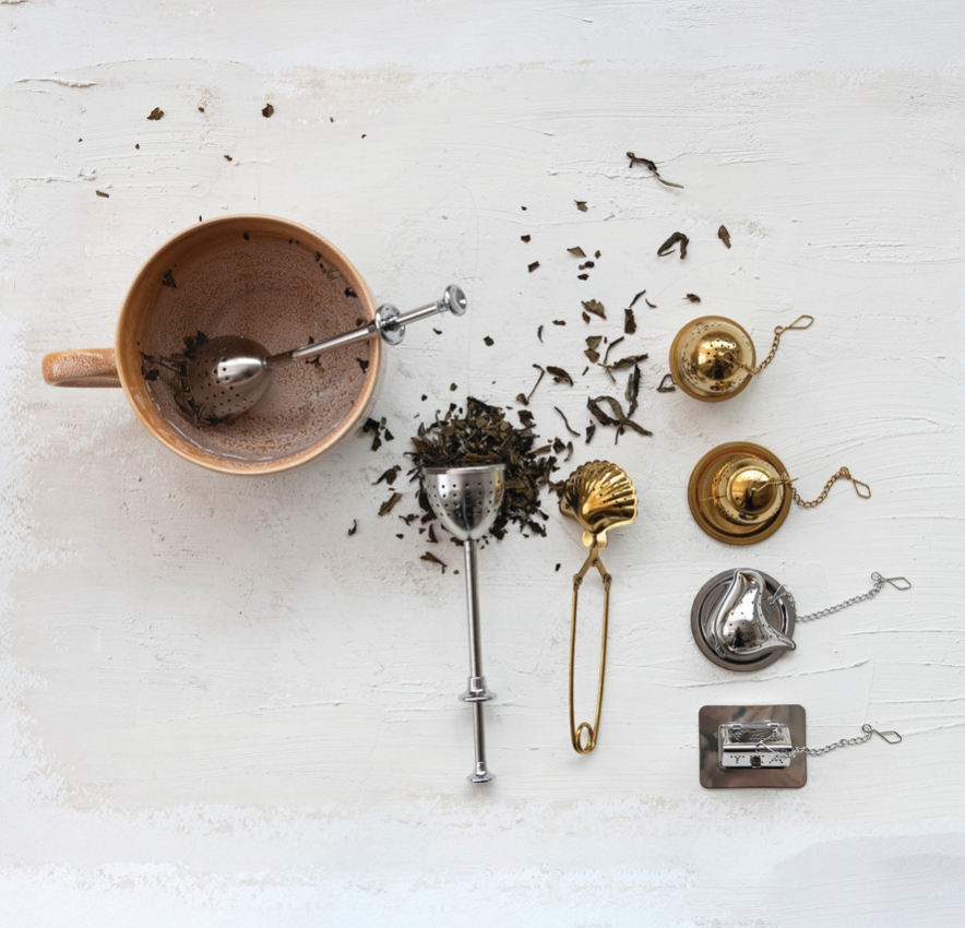 Tea-making tools including a ceramic teapot, tea leaves, and various accessories on a white surface.
