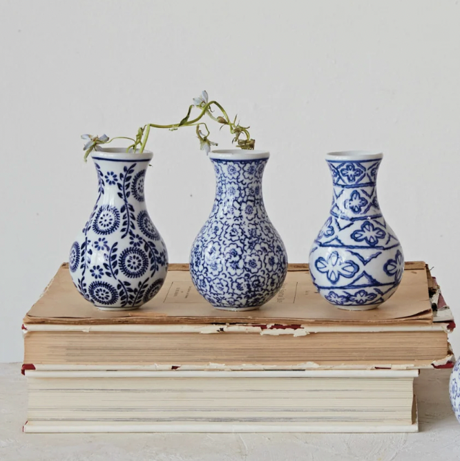Three blue and white patterned vases on a stack of books against a light background
