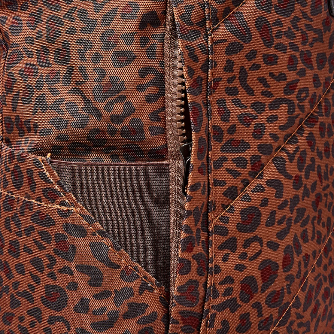 Close-up of a brown and black leopard print fabric with a diagonal zippered pocket and stitched details.