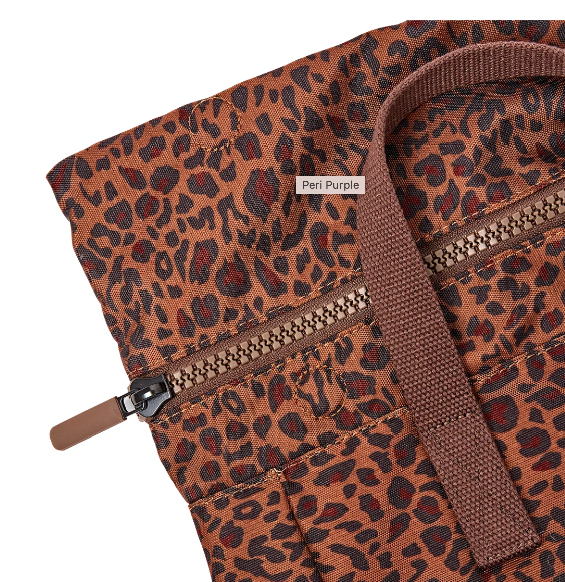 Close-up of a leopard-print fabric item in a warm brown and black pattern, with a brown zipper and a small label reading 'Peri Purple'.