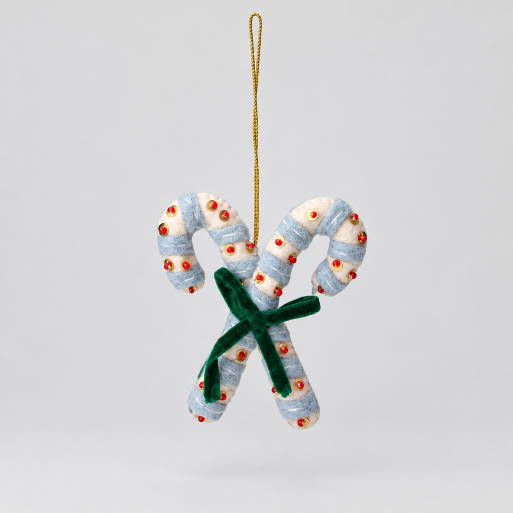 A festive felt candy cane Christmas ornament featuring two white wrapped candy canes with small red dots, tied together with a green bow, hanging from a gold string on a solid white background.