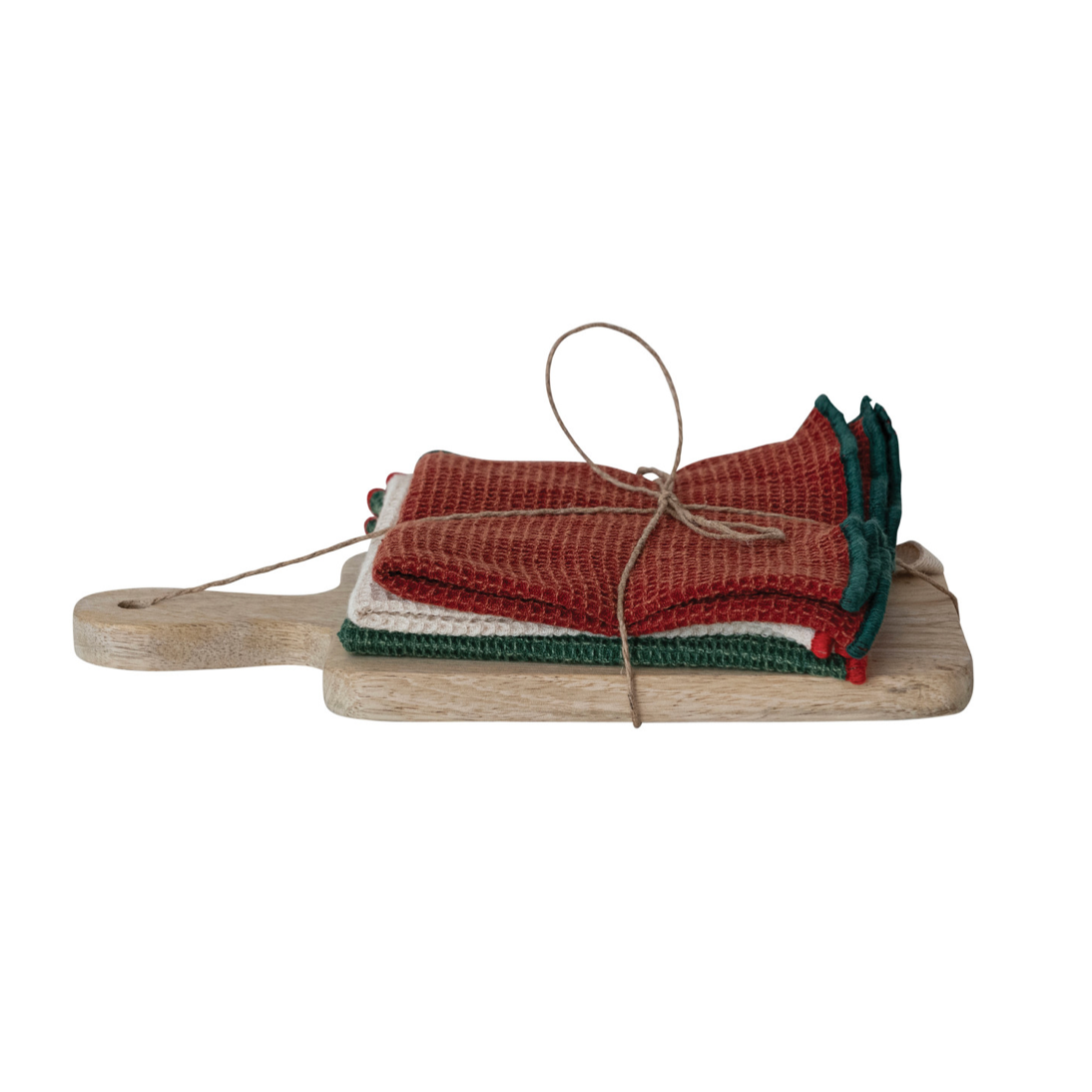 Three folded woven kitchen towels in red, cream, and green, tied with twine and displayed on a small wooden board against a white background.
