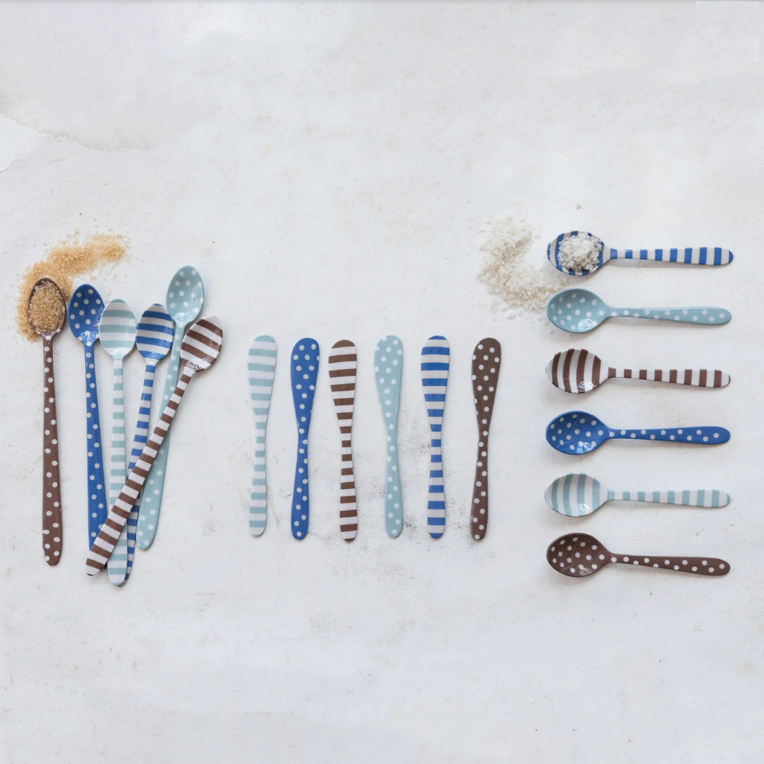 Set of patterned spoons, knives & cocktail spoons on a textured white surface