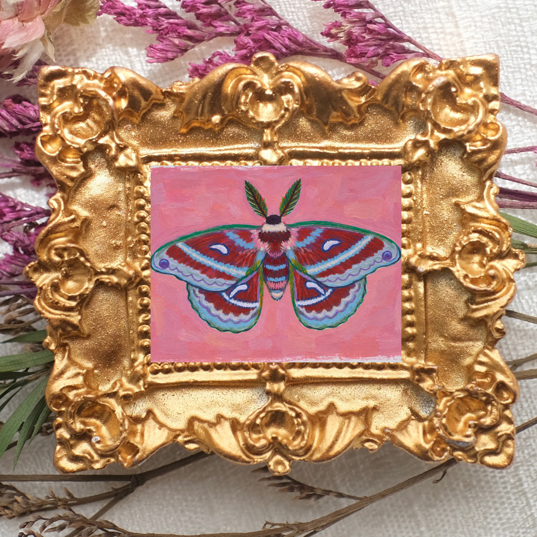 Tiny moth painting in a small ornate gold frame.