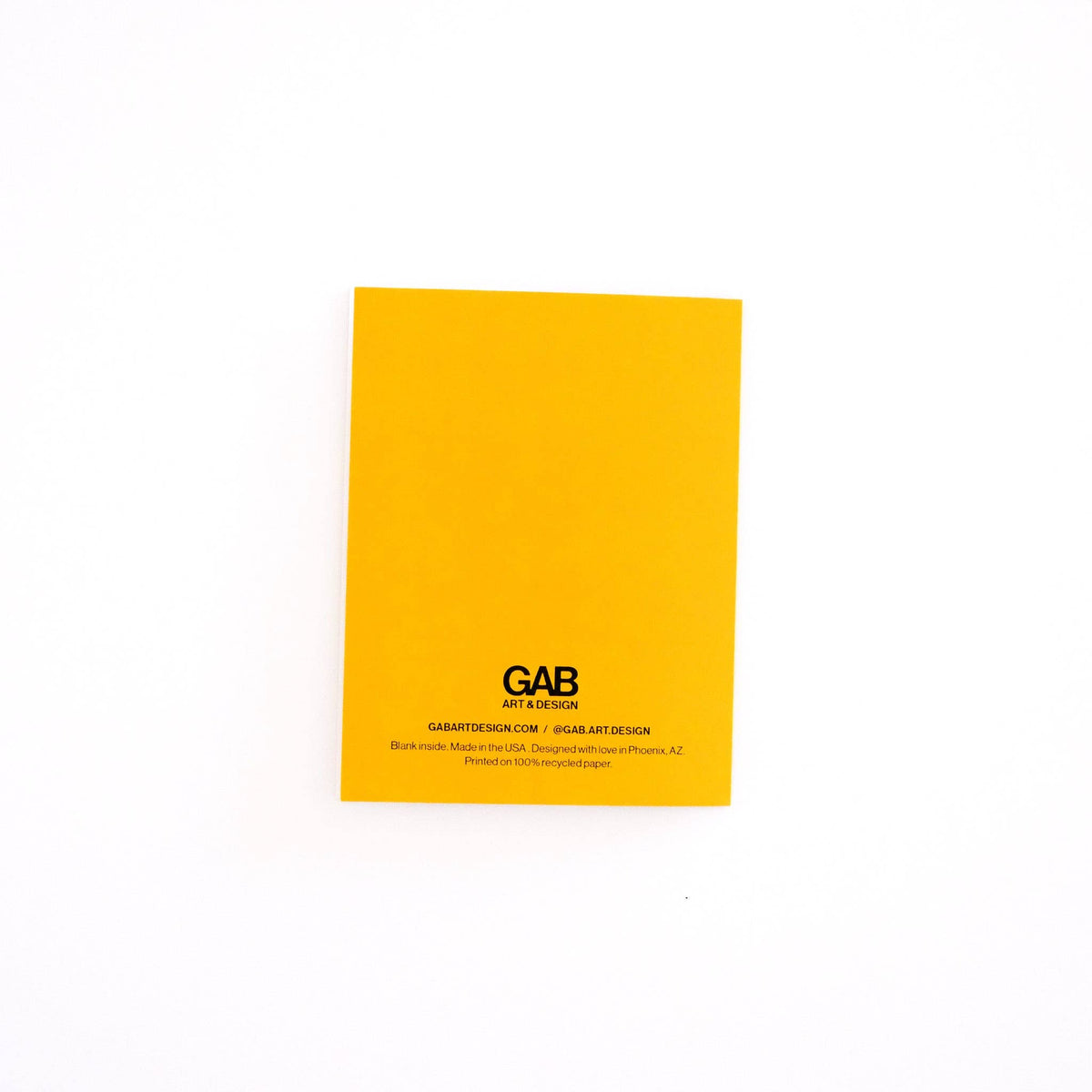 A bright yellow rectangular card or notebook cover with black printed text reading GAB art design, photographed on a plain white background.