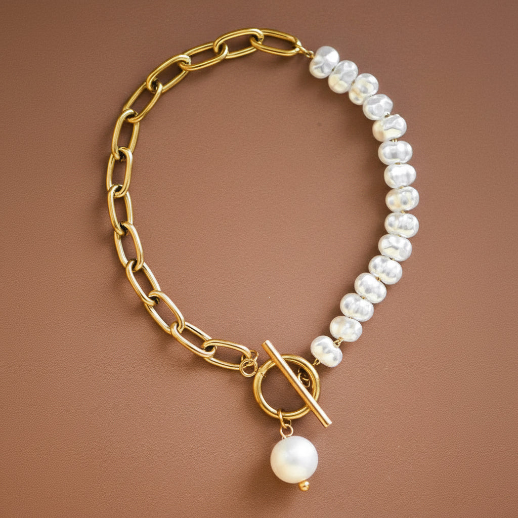 Elevate your everyday style with this stunning 18K gold plated stainless steel bracelet. Featuring a sophisticated two-tone design, one half showcases a delicate string of pearls while the other displays a sleek gold chain, connected by a secure toggle clasp. Hypoallergenic and waterproof, this piece resists tarnishing and is perfect for layering or wearing solo. Ideal for both casual and dressed-up occasions. To maintain its lustrous finish, avoid prolonged contact with lotions, perfumes, and products.