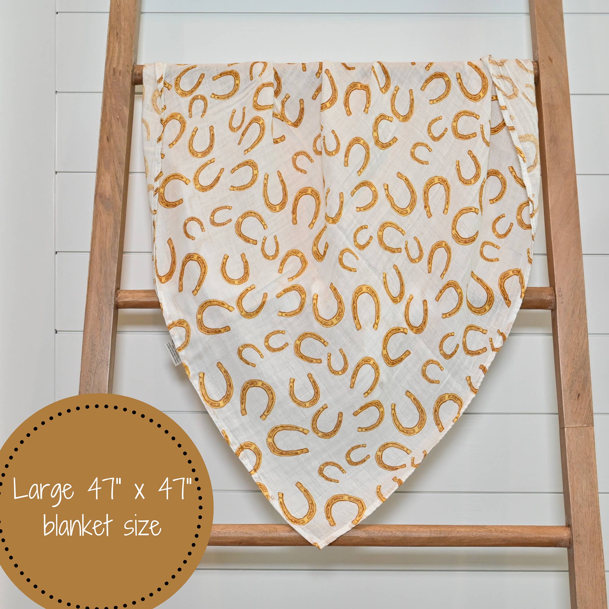 Blanket with gold horseshoe pattern draped over a wooden ladder on a white background