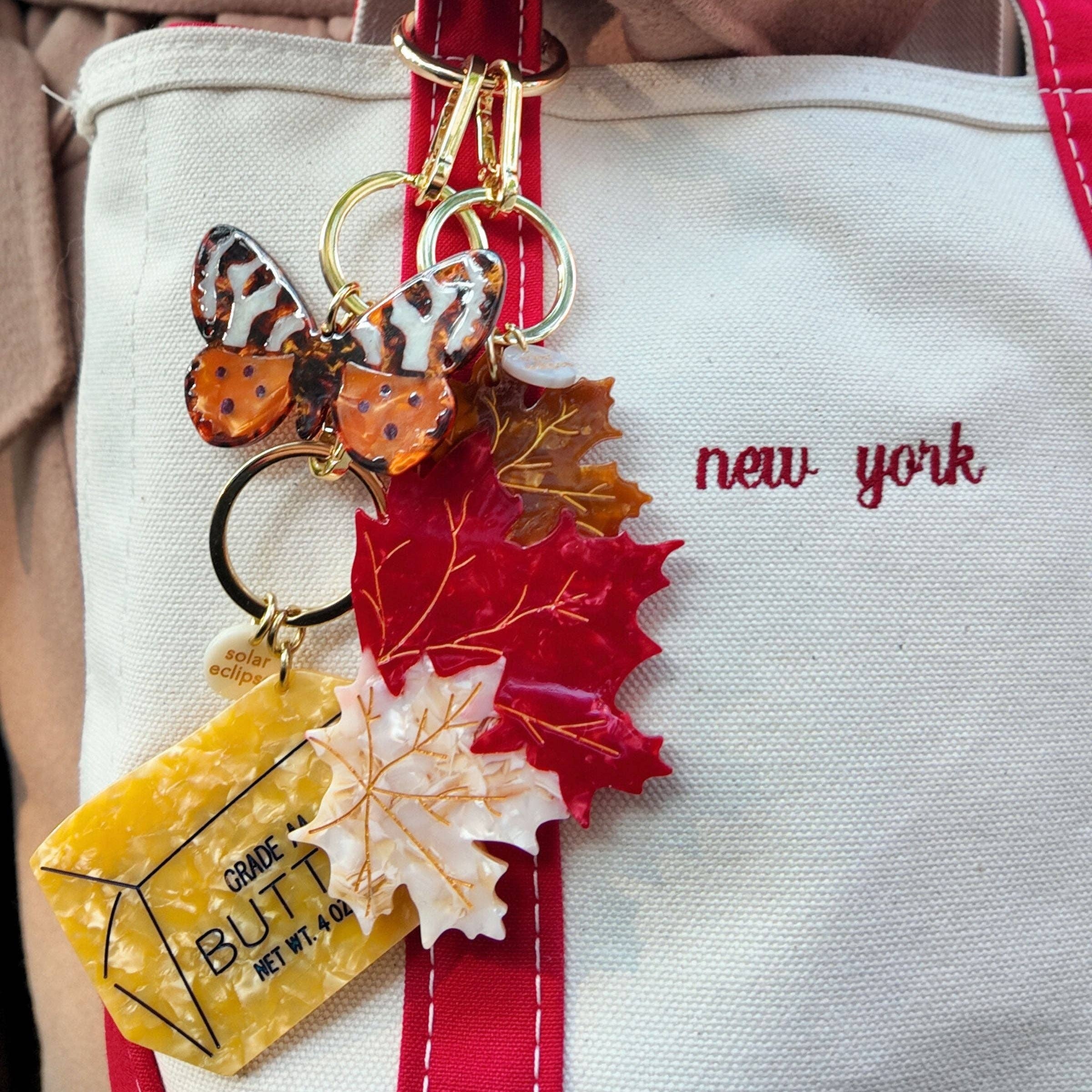 Keychain with autumn-themed charms on a tote bag labeled 'New York'.