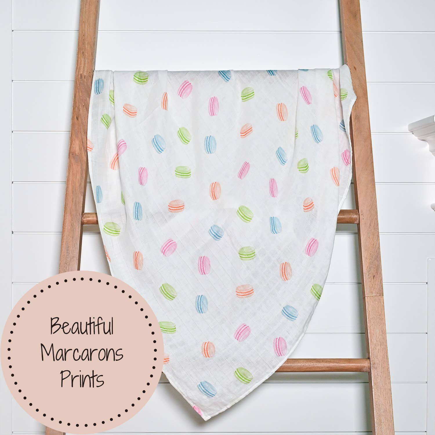 Baby blanket with colorful marcarons pattern draped over a wooden ladder on a white background.