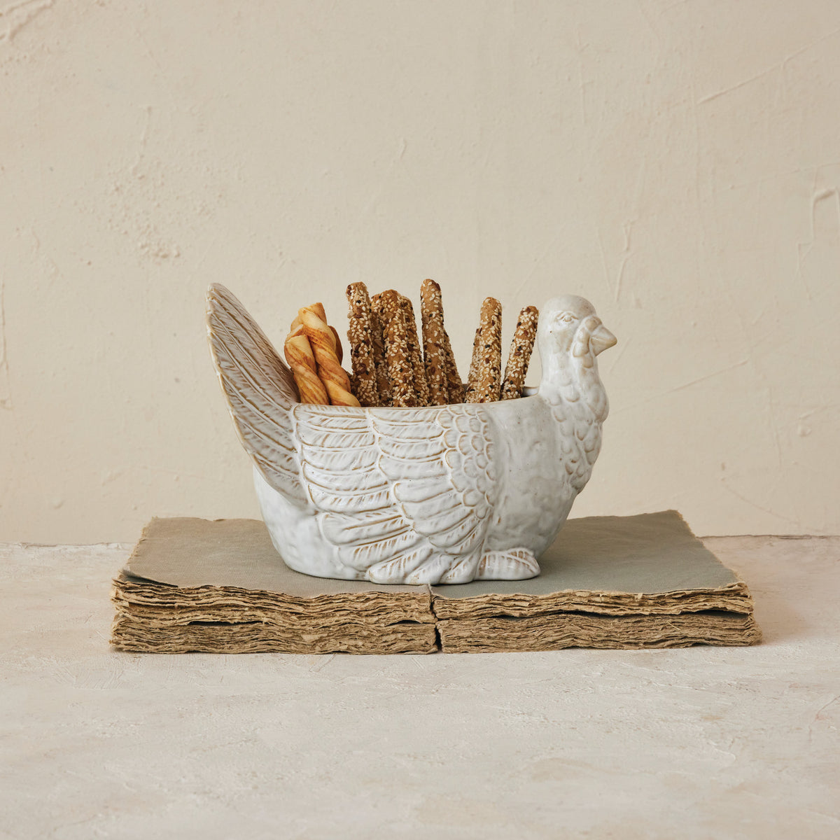 Decorative bird-shaped bread basket with bread sticks on a neutral background