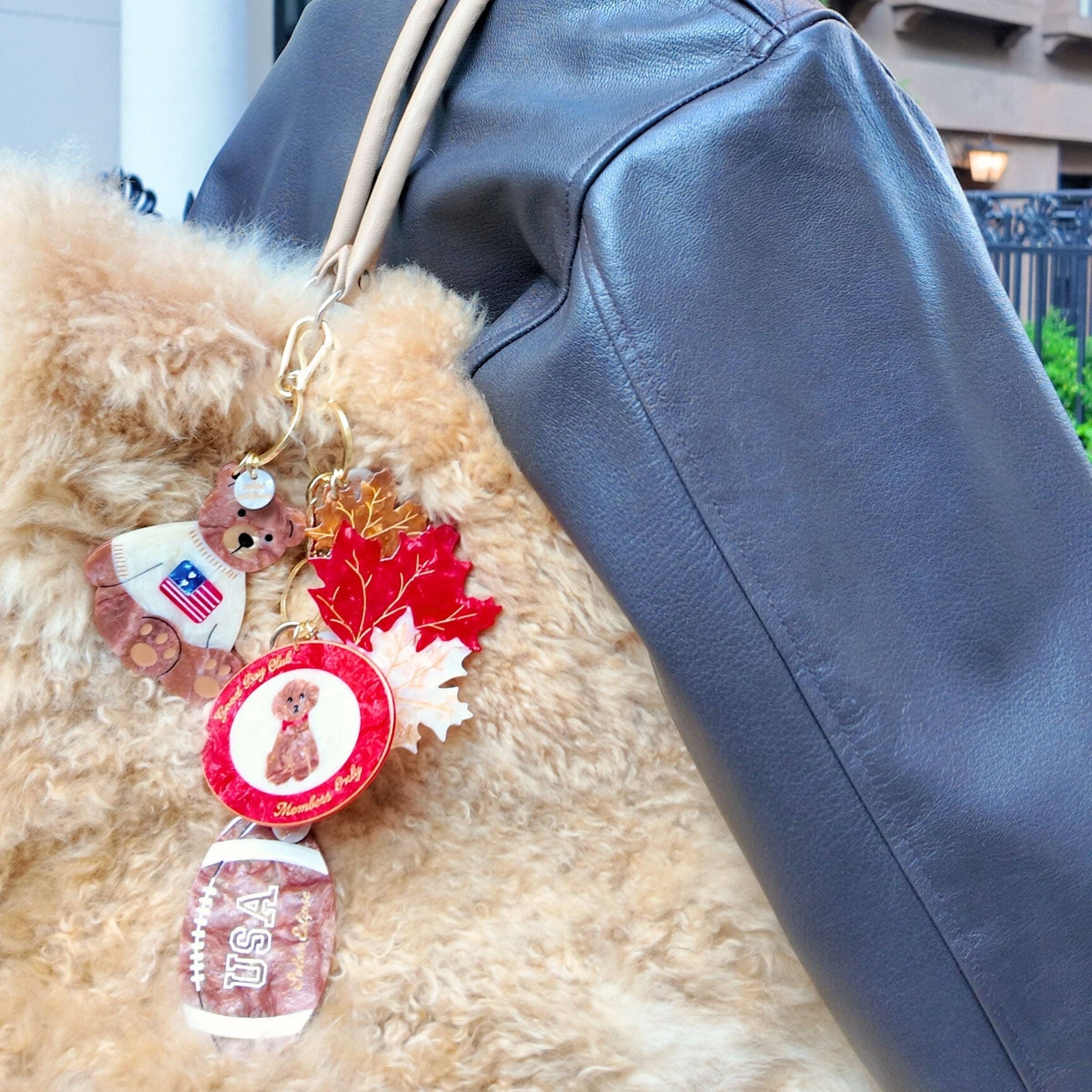 Person wearing a blue leather jacket with decorative keychain on a fur coat, outdoor setting.