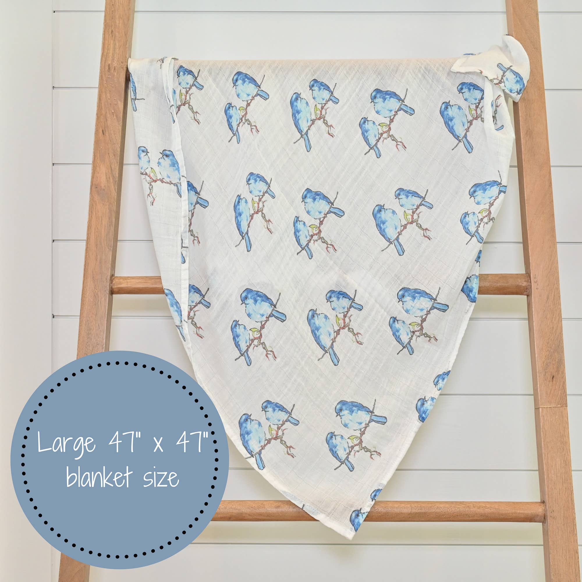 Blanket with blue bird pattern draped over a wooden ladder on a white background
