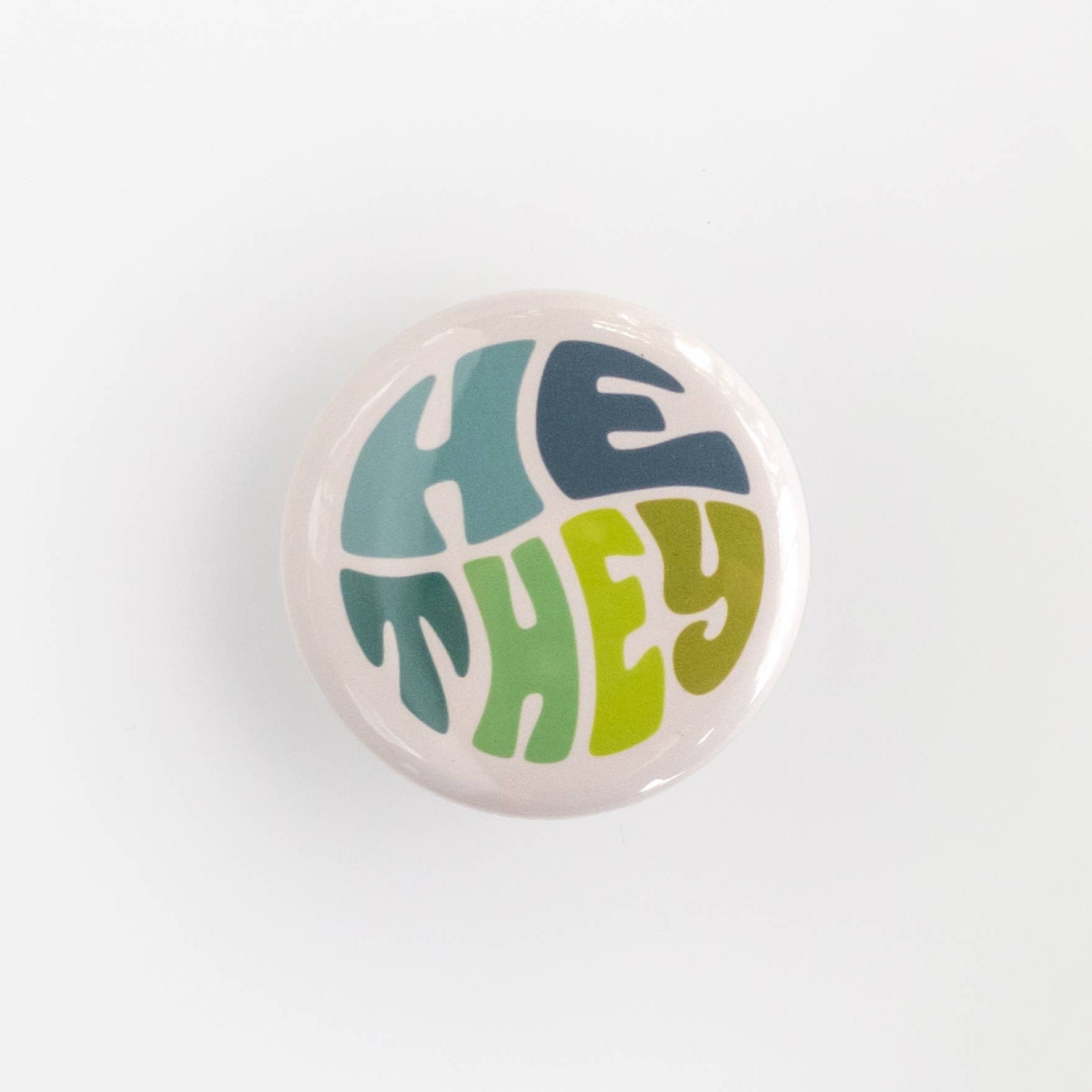 Wear your pronouns with pride with these cute retro-style buttons! This pinback button displays "He/They" pronouns in a green and blue color palette. It is the perfect way to let others know how to address you and to show your support for the LGBTQ+ community! Size: 1.25" pinback button