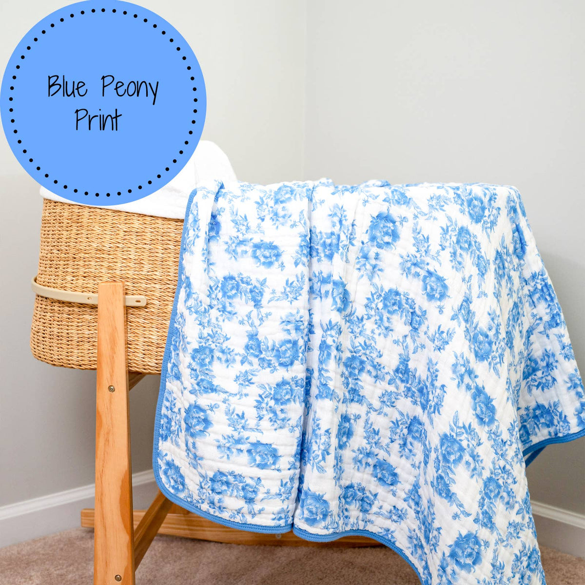 Blue peony print blanket draped over a wooden chair against a neutral wall.
