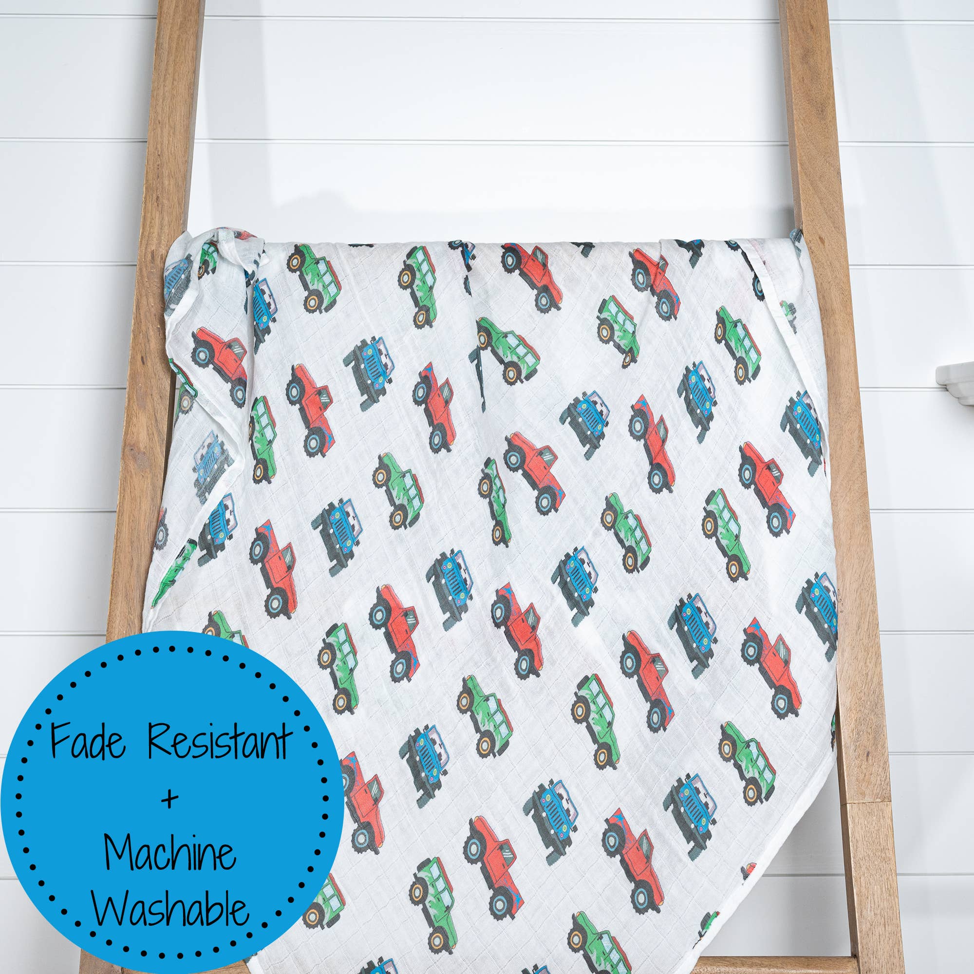 Baby blanket with car pattern on a wooden ladder against a white wall
