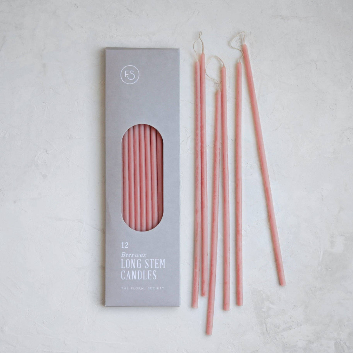 Set of pink candles with packaging on a light gray background