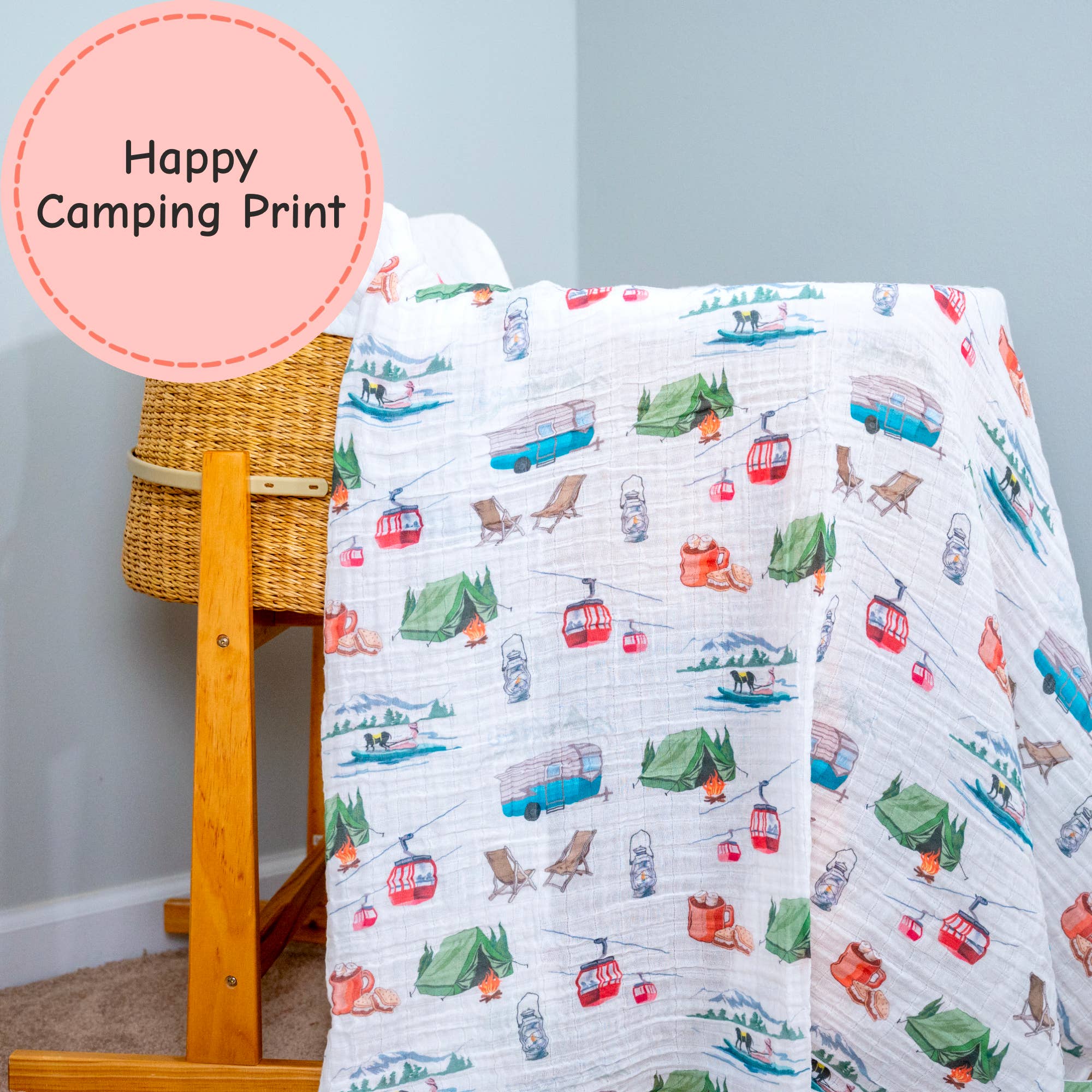 Children's blanket with camping print draped over a wooden chair against a light gray wall.
