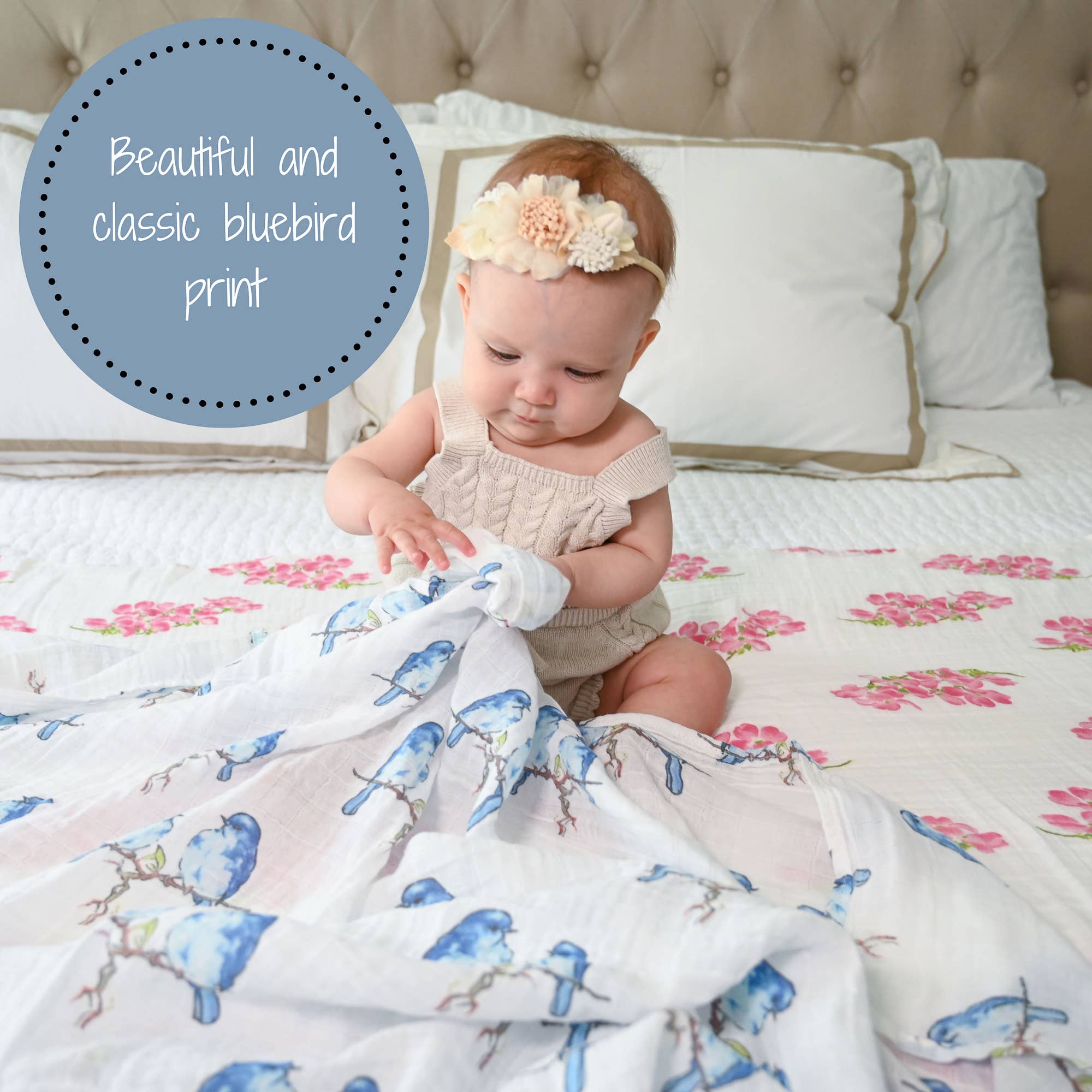 Baby sitting on a bed with a floral and bluebird patterned blanket