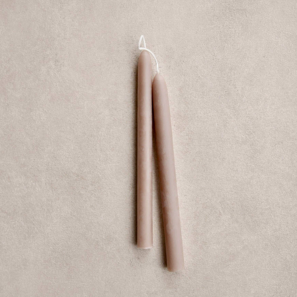 Two beige candles on a mushroom color